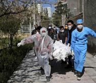 Ciudadanos con ropa protectora, máscaras y guantes llevan el cuerpo de una víctima que murió después de ser infectada con el nuevo coronavirus, en un cementerio a las afueras de Teherán, Irán. (AP)