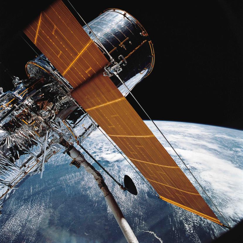 En esta foto del 25 de abril de 1990 proveída por la NASA, se ve la mayor parte del Telescopio Espacial Hubble al ser suspendido en el espacio por el transbordador Discovery tras el despliegue de sus paneles solares y su antena.