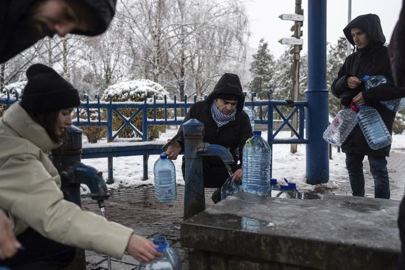 Ciudadanos recolectan agua de una toma pública que todavía funciona pese a los constantes bombardeos de Rusia a instalaciones de servicios públicos como energía y agua potable.