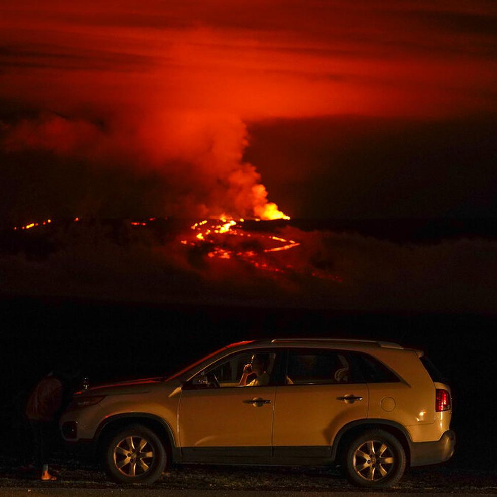 Un hombre conversa por teléfono desde su auto a lo largo de Saddle Road, la principal carretera que une las costas este y oeste de la Isla Grande de Hawai, al tiempo que el volcán Mauna Loa hace erupción el miércoles 30 de noviembre de 2022, cerca de Hilo, Hawai.