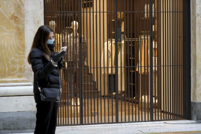 Una mujer revisa su teléfono afuera de las tiendas cerradas en el centro comercial Galleria Umberto, en el centro de Nápoles, Italia, el miércoles 11 de marzo de 2020. (Alessandro Pone/LaPresse via AP)