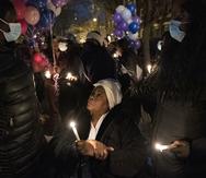 Un familiar se reúne con miembros de la comunidad para una vigilia con velas para recordar a quienes perecieron en el incendio de una casa en Filadelfia.