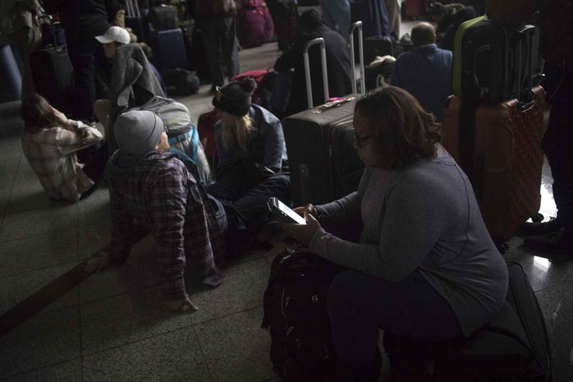 Varios pasajeros esperan a que regrese la luz en el aeropuerto internacional Hartsfield-Jackson de Atlanta tras un apagón. (AP)