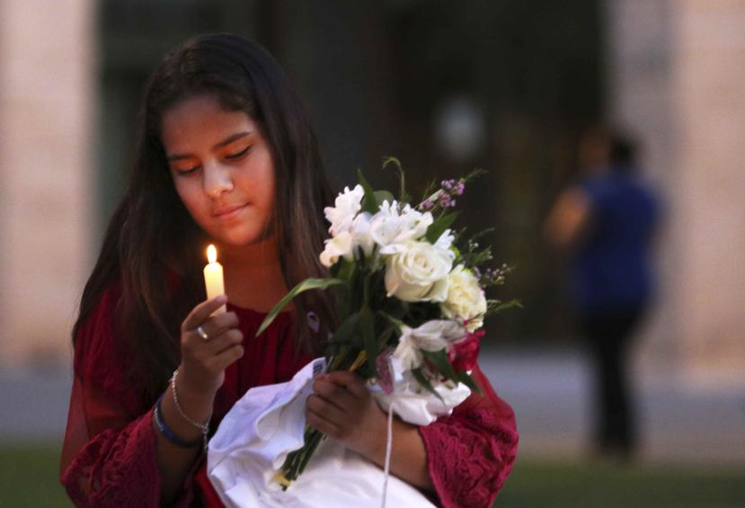 Jaxciri Solano enciende una vela y sostiene un ramo de flores al inicio de una vigilia en el campus de UTPB en Odessa, Texas. (Ben Powell / Odessa American via AP)