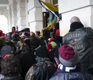 ARCHIVO - Un grupo de leales al expresidente Donald Trump intenta abrir una puerta del Capitolio de Estados Unidos mientras se amotinan en Washington, el 6 de enero de 2021.