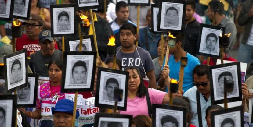 Manifestantes marchan con carteles recordatorios de los estudiantes de Ayotzinapa. (AP)