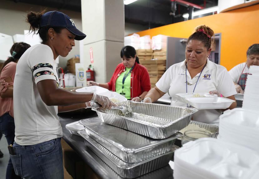 Empleadas del municipio de San Juan sirven alimentos en un refugio.