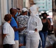 Una trabajadora de la salud habla con varias personas en La Habana.