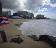 Una bandera de Puerto Rico ondea en una playa vacía en Ocean Park, el jueves 21 de mayo de 2020, en San Juan. (AP Foto/Carlos Giusti, Archivo)