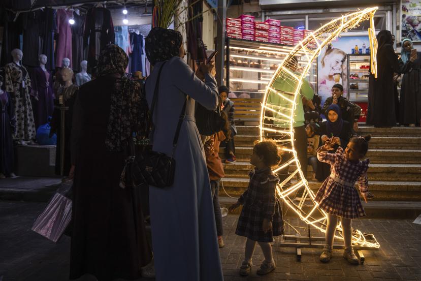 Una mujer toma fotos a su hija junto a una decoración con forma de luna creciente en un mercado, en el inicio del mes sagrado musulmán del Ramadán, en el campo de refugiados de Jebaliya, en el norte de la Franja de Gaza.