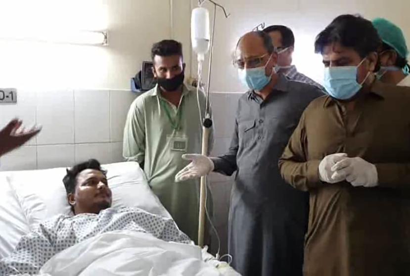 El ministro de Salud de la región paquistaní, Saeed Ghani (segundo por la derecha), saluda a Mohammad Zubair, quien sobrevivió a un accidente de avión, en un hospital en Karachi, Pakistán. (AP)