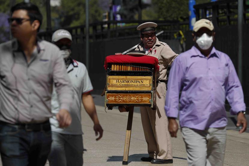 El organillero Moisés Rosas pide propinas a los peatones en el centro de Ciudad de México. Rosas que lleva 25 años como organillero, dijo no tener miedo al coronavirus y necesita los 200 pesos de media que gana al día. (AP)