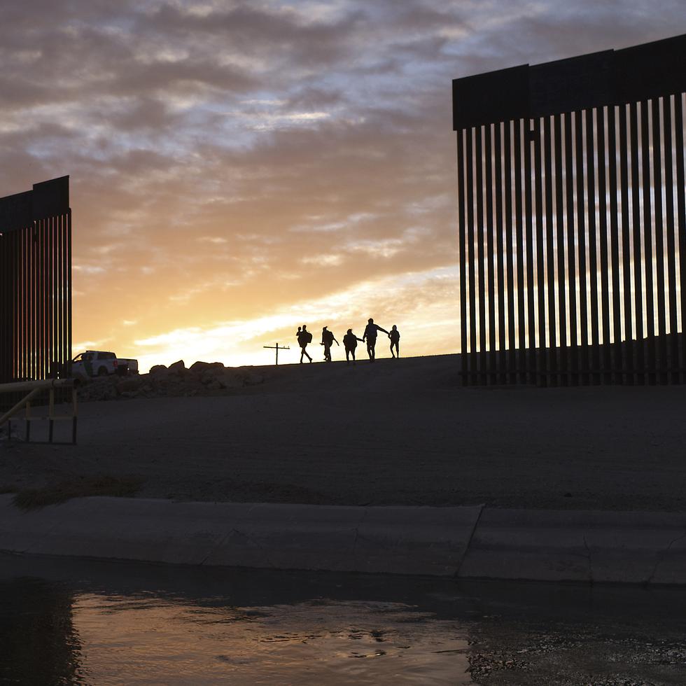 Un par de familias migrantes de Brasil atraviesan un hueco en el muro fronterizo para llegar a Estados Unidos después de cruzar desde México en Yuma, Arizona.
