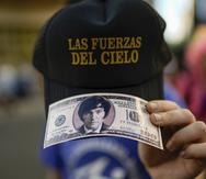 A supporter of the opposition presidential candidate Javier Milei holds a reproduction of a hundred dollar bill featuring the candidate's face outside his campaign headquarters after the polls closed in the presidential runoff election in Buenos Aires, Argentina, Sunday, Nov. 19, 2023. (AP Photo/Rodrigo Abd)