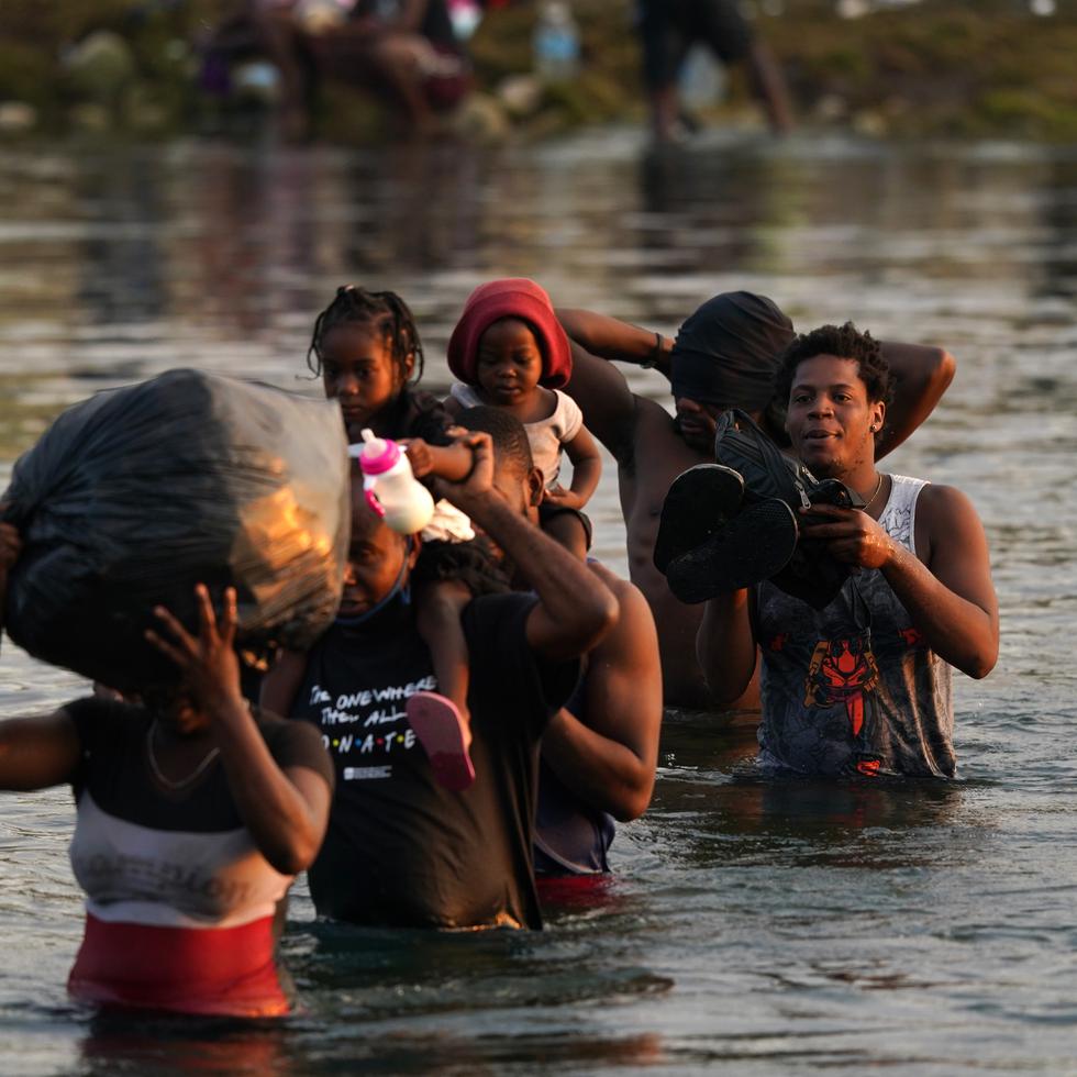 Migrants, many from Haiti, wade across the Rio Grande from Del Rio, Texas, to return to Ciudad Acuna, Mexico, Tuesday, Sept. 21, 2021, to avoid deportation from the U.S.  The U.S. is flying Haitians camped in a Texas border town back to their homeland and blocking others from crossing the border from Mexico. (AP Photo/Fernando Llano)