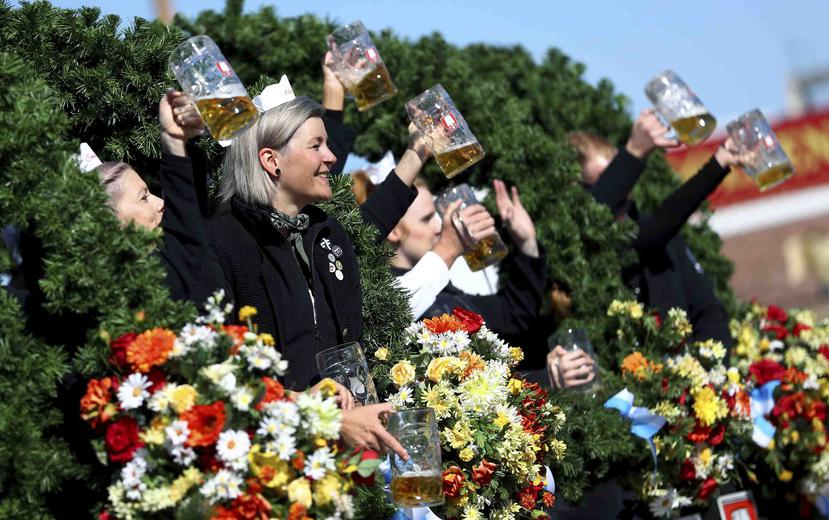 Gente con vestimenta tradicional alza sus jarras de cerveza en la inauguración de la 186ta Oktoberfest, Munich, Alemania. (AP)