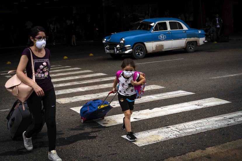 Turistas salen del aeropuerto José Martí, en Cuba, utilizando mascarillas como prevención al coronavirus. (AP)