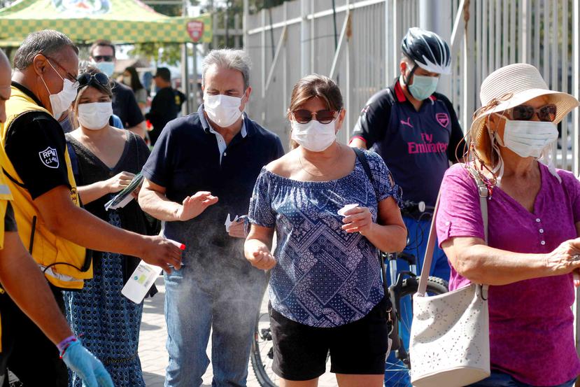 Chilenos mientras reciben desinfectante en medio de la pandemia de coronavirus.
