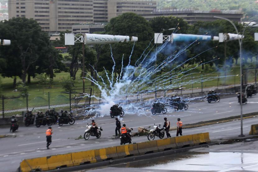 Fuegos artificiales lanzados por manifestantes antigubernamentales explotan cerca de las fuerzas de seguridad que circulan en motocicletas en Caracas, Venezuela. (AP)
