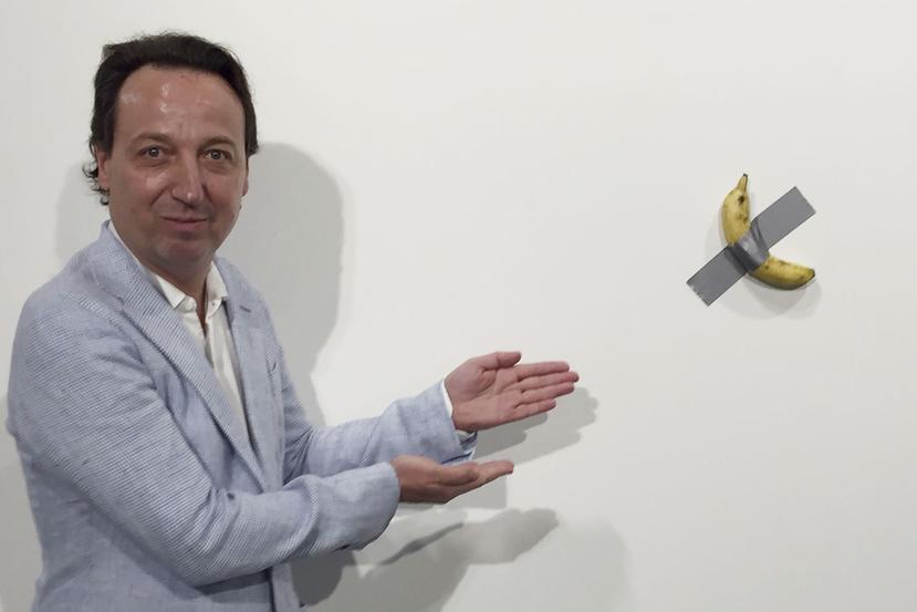 El dueño de galería Emmanuel Perrotin posa junto a la obra "Comedian" del artista italiano Maurizio Cattlelan durante su exhibición en la feria Art Basel Miami, en Miami Beach, Florida. (Siobhan Morrissey vía AP)
