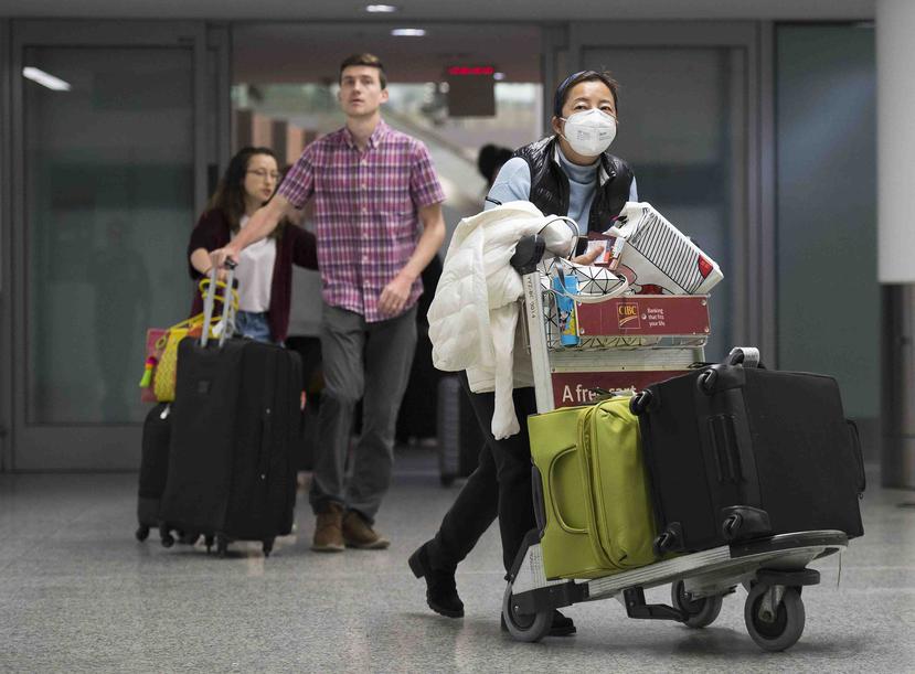 Una mujer con mascarilla camina por un avión a en la zona de llegadas de la terminal internacional del aeropuerto Toronto Pearson en Toronto. (AP)