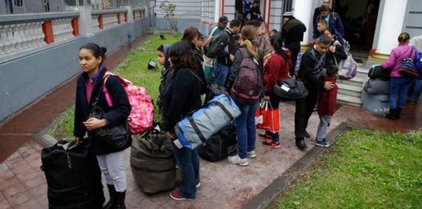 Migrantes venezolanos esperan afuera de la embajada de su país un autobús que los transportará al aeropuerto, en Lima, Perú. (AP)