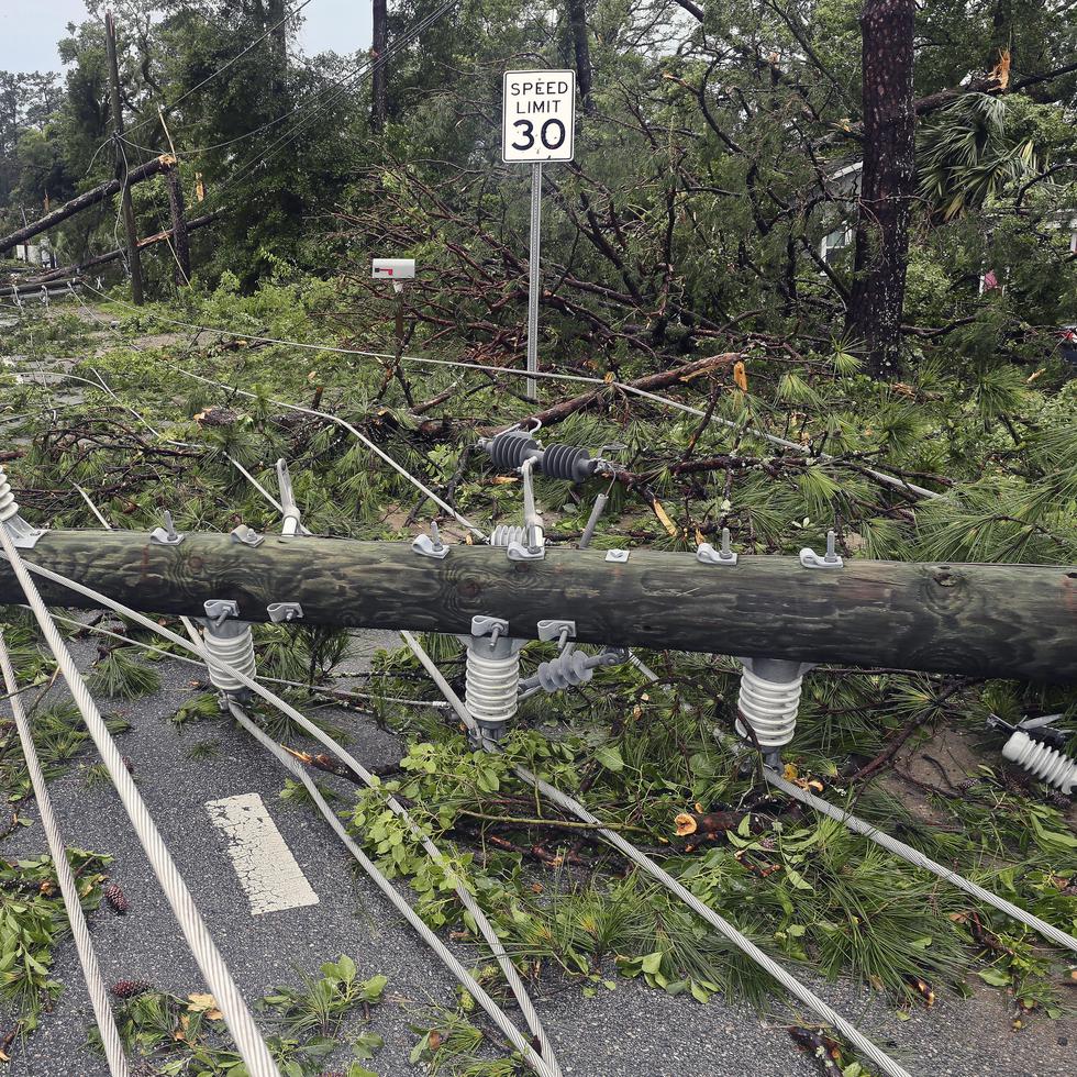 Cuadrillas de trabajadores retiran postes quebrados y cableado eléctrico derribado por los fuertes vientos, en una calle de Tallahassee, Florida.