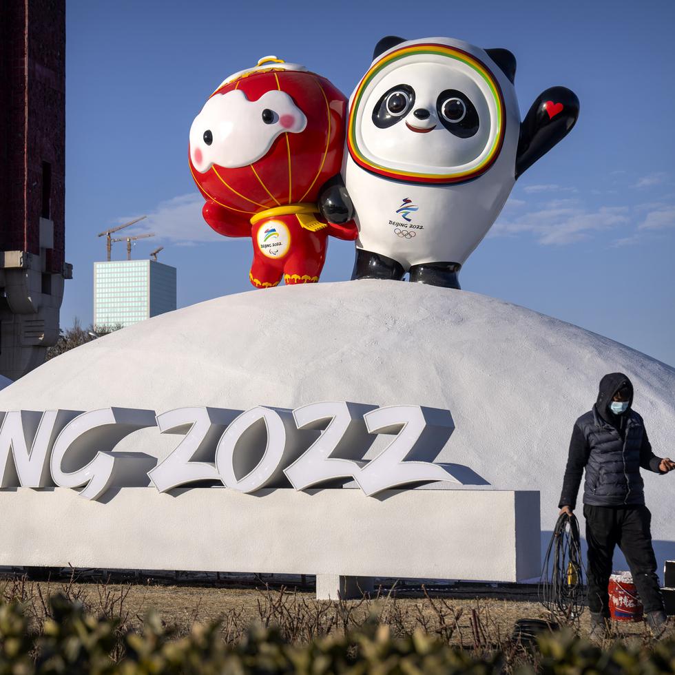 Un empleado camina frente a las mascotas de los Juegos Olímpicos y Paraolímpicos de Invierno de Pekín.