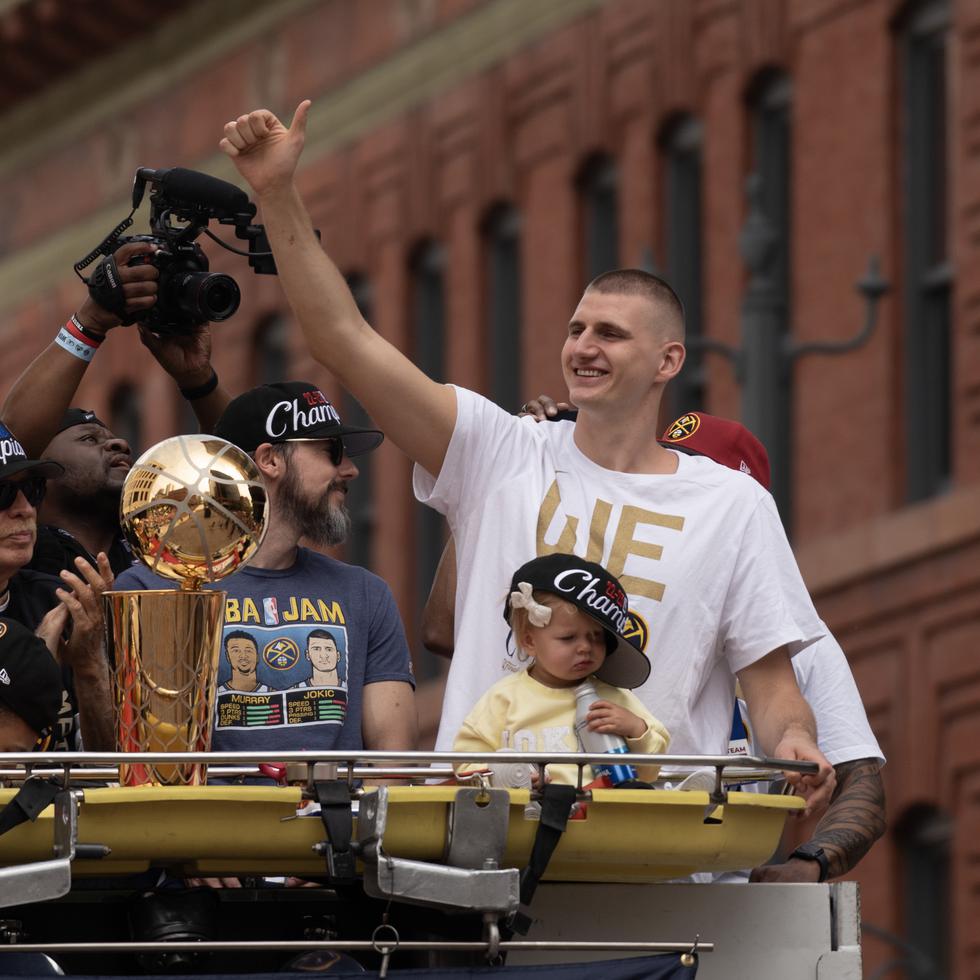 El pívot de los Denver Nuggets Nikola Jokic (d) encabeza el acto de celebración del título de la NBA, este 15 de junio de 2023, a bordo de un camión de bomberos junto al trofeo de campeones y el de MVP, en Denver Colorado.