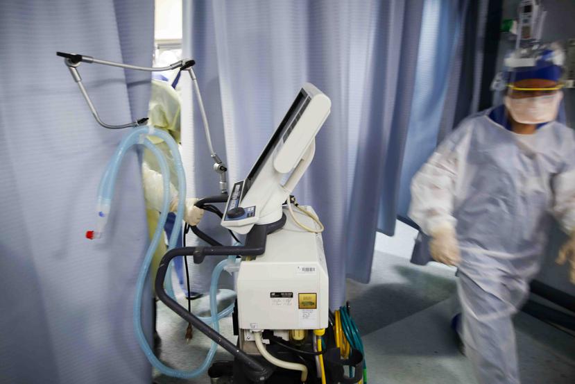 Una enfermera lleva un respirador a una sala de examen donde un paciente que dio positivo por COVID-19 repentinamente sufrió un paro cardíaco después de aparecer estable momentos antes. (AP)