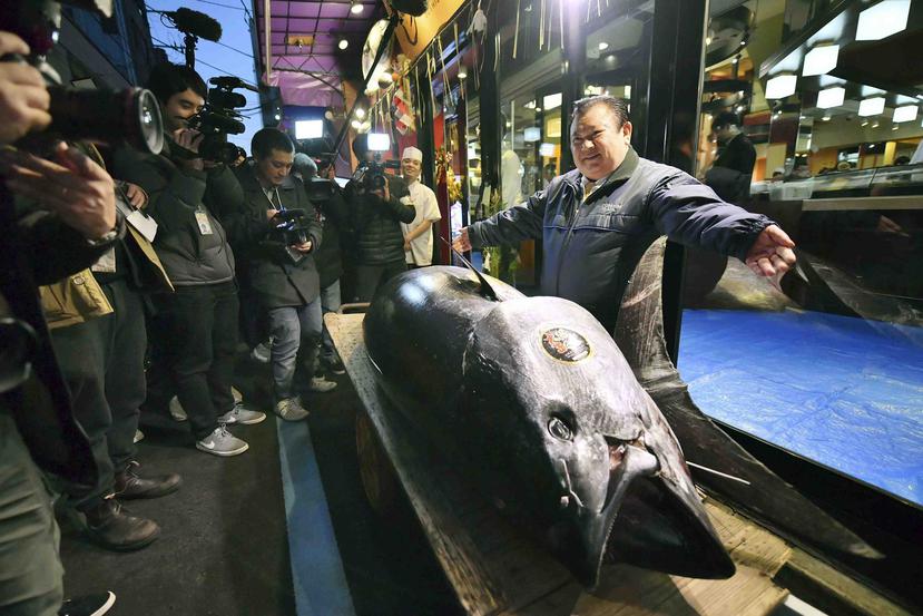 El propietario de Kiyomura Corp. Kiyoshi Kimura, a la derecha, posa junto al atún aleta azul que compró en una subasta durante la subasta de Año Nuevo frente a su restaurante Sushi Zanmai en Tokio. (AP)