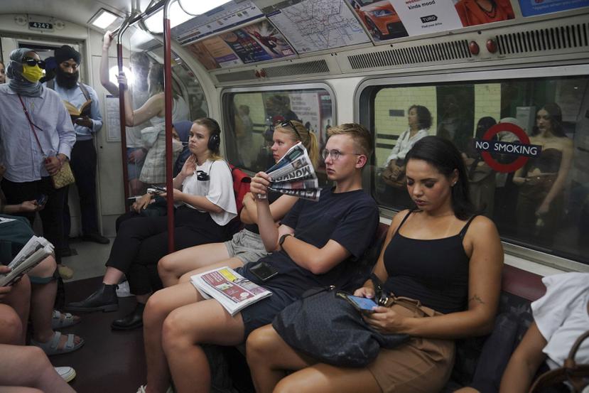 Un hombre usa un periódico para abanicarse mientras viaja en la línea Bakerloo en el centro de Londres durante la ola de calor, el lunes 18 de julio de 2022.