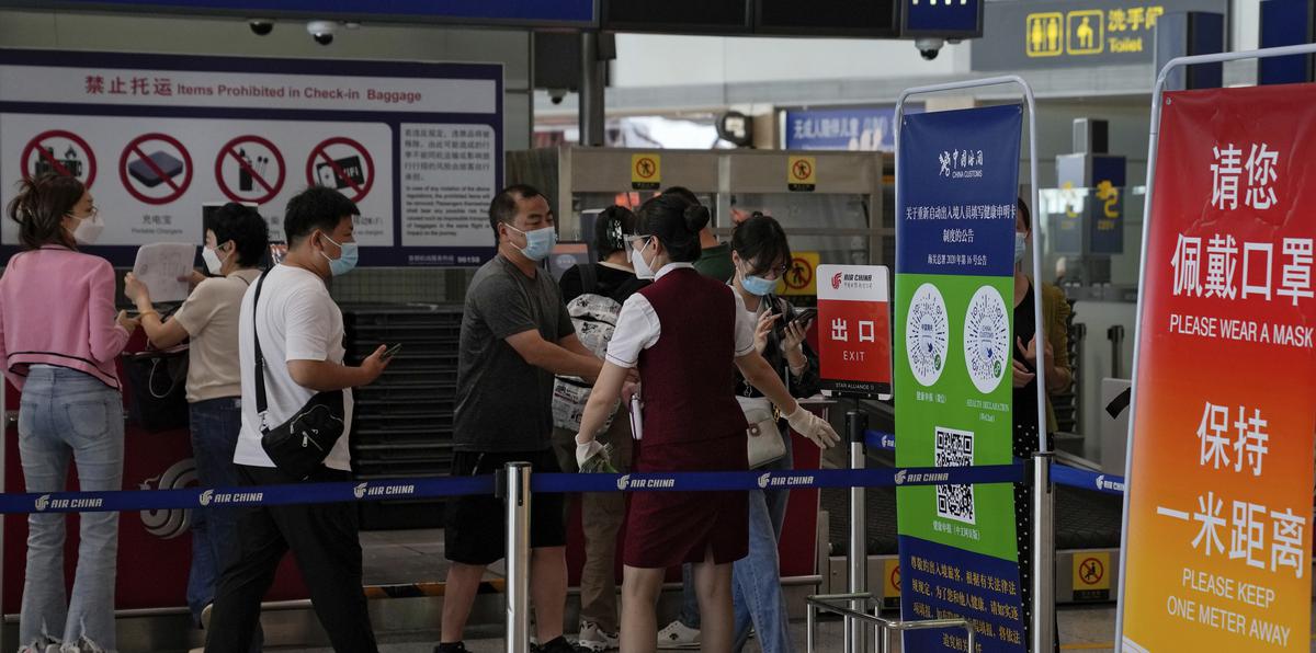 Una trabajadora aérea pide a los viajeros que declaren su información de salud tras facturar en el mostrador de vuelos internacionales en el aeropuerto internacional de Pekín.