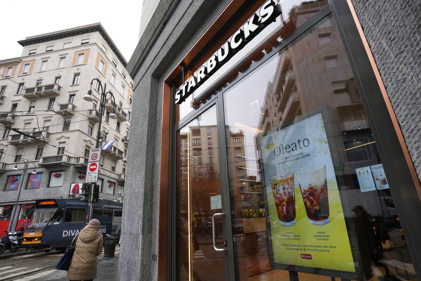 Un letrero que anuncia el café Oleato se destaca en el frente de una cafetería de la cadena Starbucks en Milán, Italia, el lunes 27 de febrero de 2023. Añadir aceite de oliva al café no es una tradición en Italia, pero eso no impidió que Howard Schultz, director general interino de Starbucks, lanzara una serie de bebidas que combinan ambos ingredientes y que actualmente se ofrecen en Milán, la ciudad que inspiró su imperio de cafeterías. (AP Foto/Antonio Calanni)