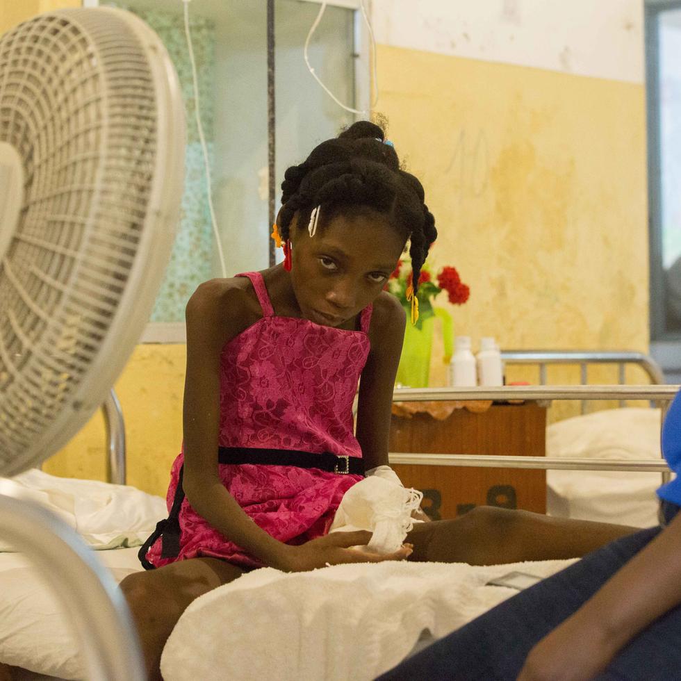 Amazon Annegardine, de 11 años, que recibe tratamiento por niveles anómalos de azúcar en sangre, se sienta en una cama junto a su madre en el Hospital de la Inmaculada Concepción, en Les Cayes, Haití.
