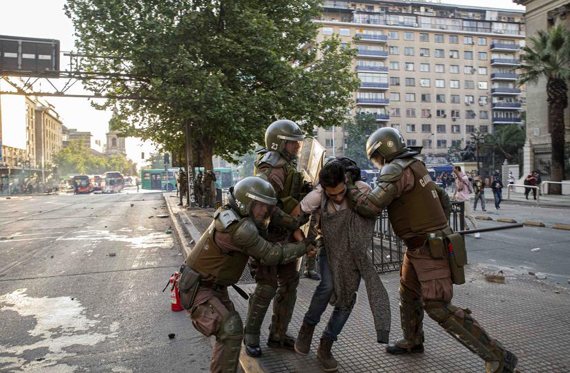 Agentes de policía chilena detienen a un hombre durante una protesta contra el aumento de las tarifas del metro y los autobuses. (AP)