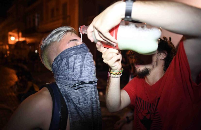 Una persona hecha leche sobre los ojos de un manifestante que resultó afectado por gases lacrimógenos.