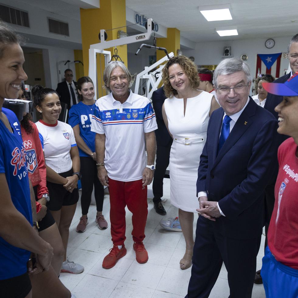 A extrema izquierda, Thomas Bach comparte con varios atletas que estaban entrenando en el gimnasio de la Casa Olímpica. Arriba, junto a la presidenta del Copur, Sara Rosario, en la apertura de una exposición en Plaza Las Américas.