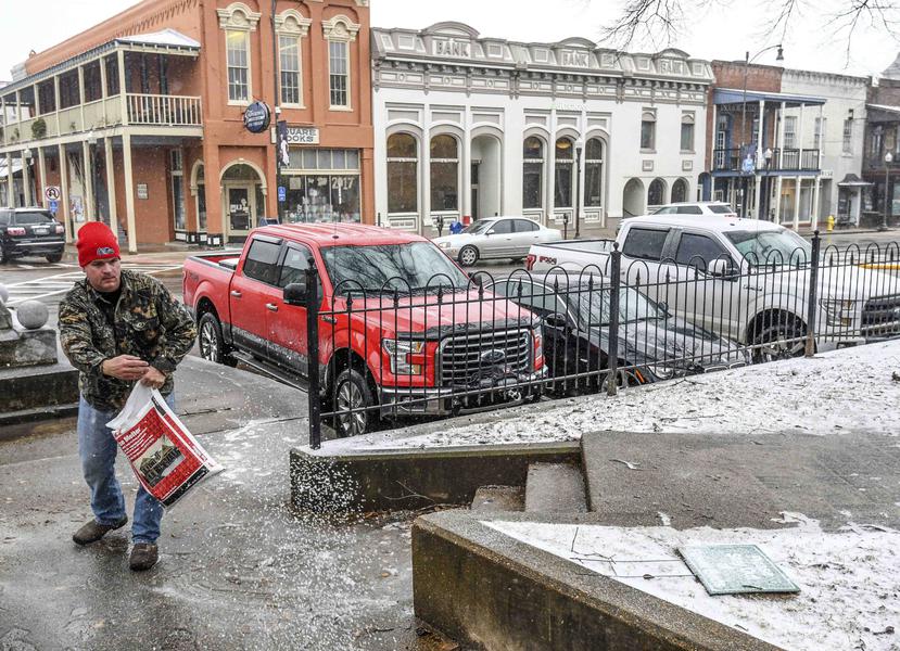 Un ciudadano esparce una sustancia para derretir hielo en la acera fuera del tribunal del condado de Lafayette en Oxford, Mississippi. (AP)