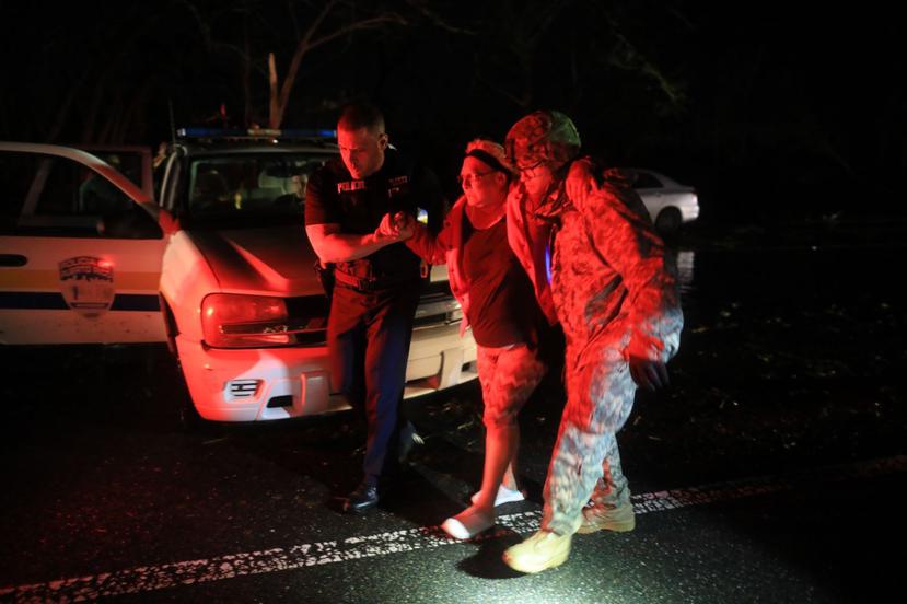Un agente de la Policía Municipal de Toa Baja y un soldado rescatan a una mujer de la inundación en Toa Baja.