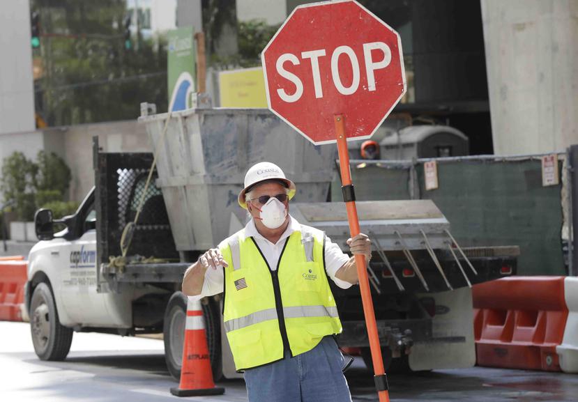 Un trabajador dirige el tránsito con una mascarilla en el centro de Miami, Florida. (AP)