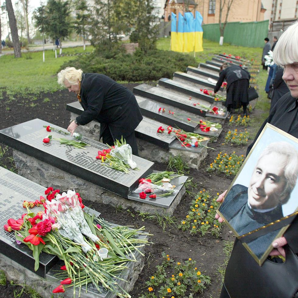 KIV07 KIEV (UCRANIA) 26/04/04.- Una mujer ucraniana muestra el retrato de un amigo que murió como resultado de la catástrofe de la planta nuclear de Chernobil mientras visita su tumba cerca del monumento a las víctimas de Chernobil en Kiev (Ucrania) hoy lunes de 26 de abril de 2004. Los ucranianos recuerdan el 18 aniversario de la catástrofe en la planta nuclear que tuvo lugar la noche del 26 de abril de 1986. EFE/Sergey Dolzhenko  