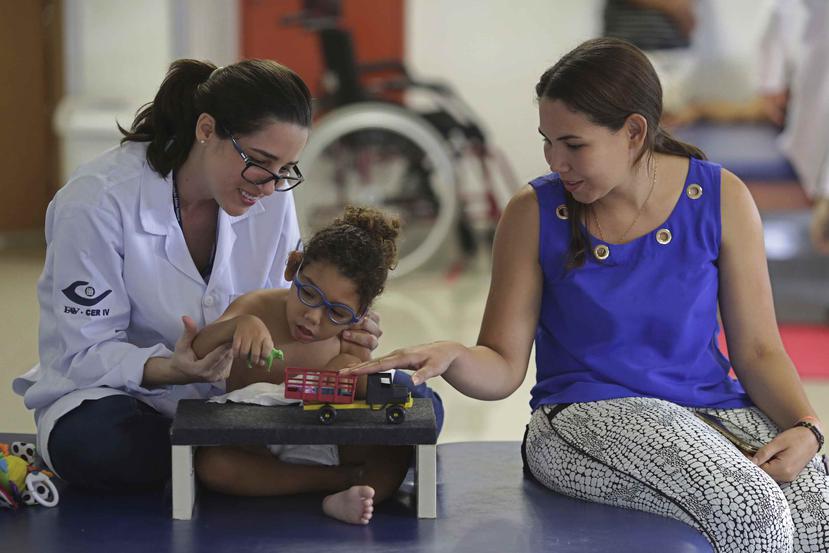Maria de Fatima (derecha) acompaña a su hijo de 18 meses, Joaquim, que nació con microcefalia provocada por el zika, durante una sesión de destreza manual con la terapeuta Catarina Aquino, en el Instituto Altino Ventura, en Recife, Brasil. (AP)