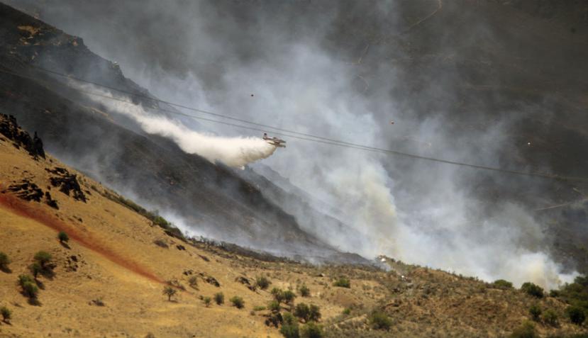 Imagen que muestra a una avioneta dejando caer agua sobre un incendio forestal al este de Portland, Oregon (AP).