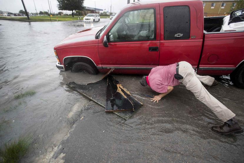 Felipe Morales trataba ayer de sacar su carro de una zanja inundada en Houston. (AP)