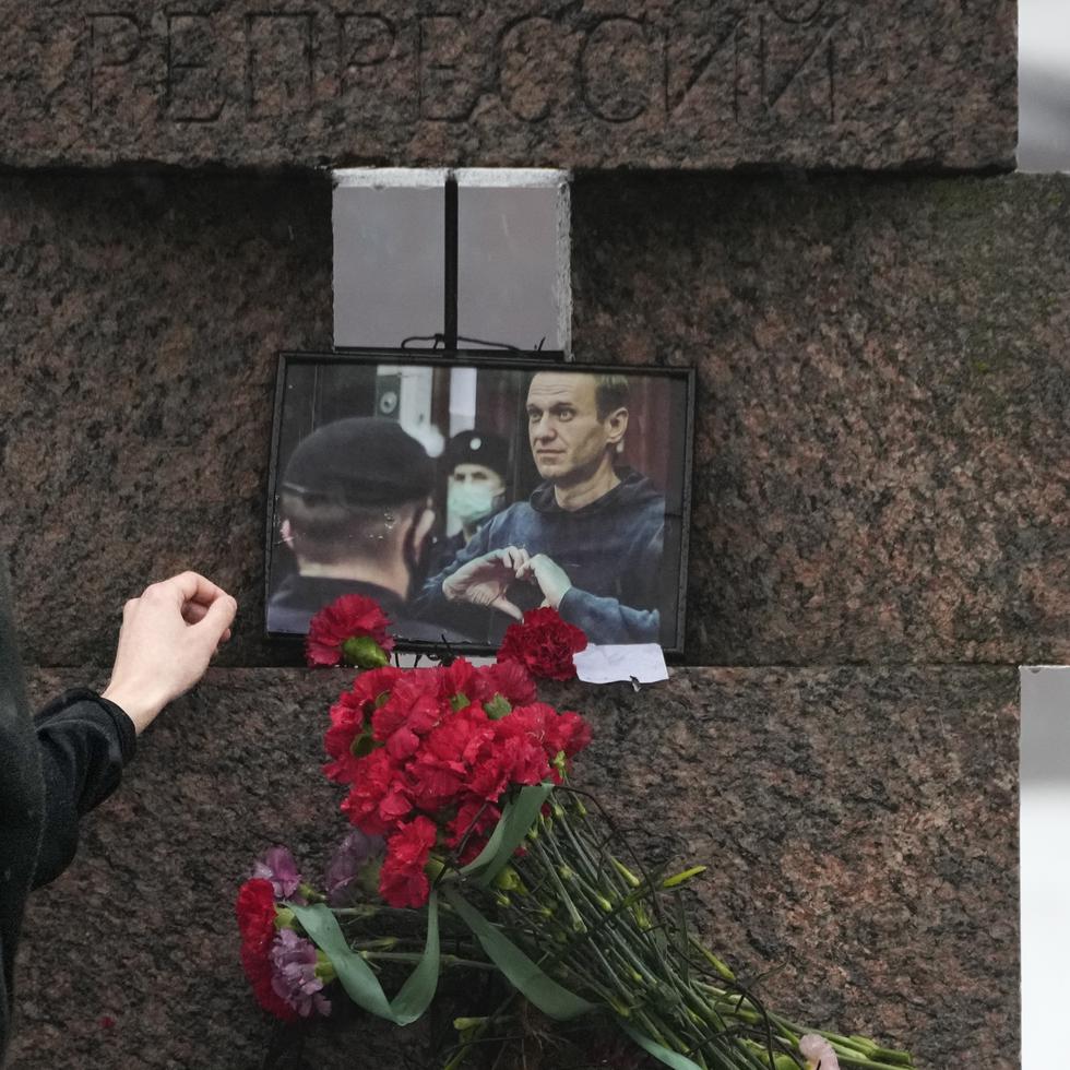 Una mujer toca la fotografía de Alexei Navalny tras dejar flores en homenaje al fallecido líder opositor ruso, en San Petersburgo, Rusia, el sábado 17 de febrero de 2024. (AP Foto/Dmitri Lovetsky)