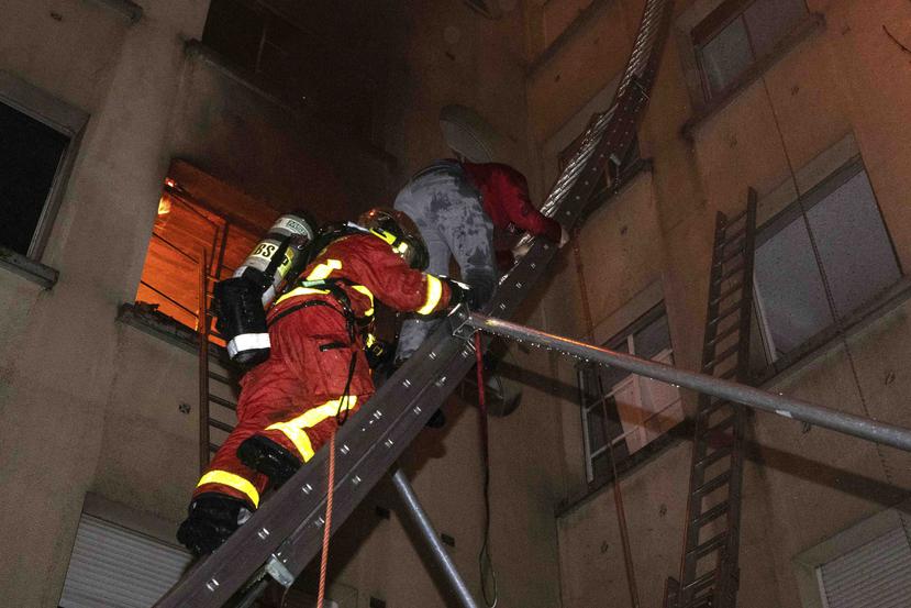Imagen proporcionada el martes 5 de febrero de 2019 por la Brigada de Bomberos de París del residente de un edificio residencial mientras un bombero le ayuda a escapar de un incendio en París, Francia. (Benoit Moser/BSPP vía AP)