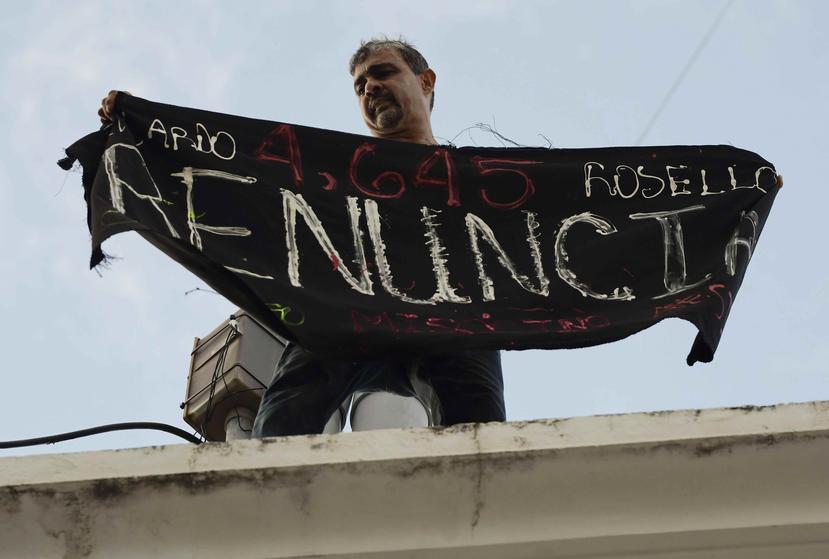 Momento en que Alberto de Jesús desplegó el cartel sobre el techo de la Comandancia de la Policía en la calle Fortaleza el pasado domingo. (AP / Carlos Giusti)
