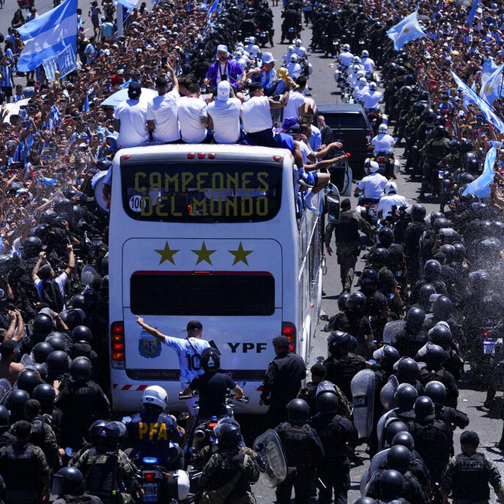 The Argentine soccer team shows off their World Cup trophy from a bus as they are welcomed home in Buenos Aires, Argentina, Tuesday, Dec. 20, 2022. The bus window reads in Spanish "World Champions." (AP Photo/Natacha Pisarenko)