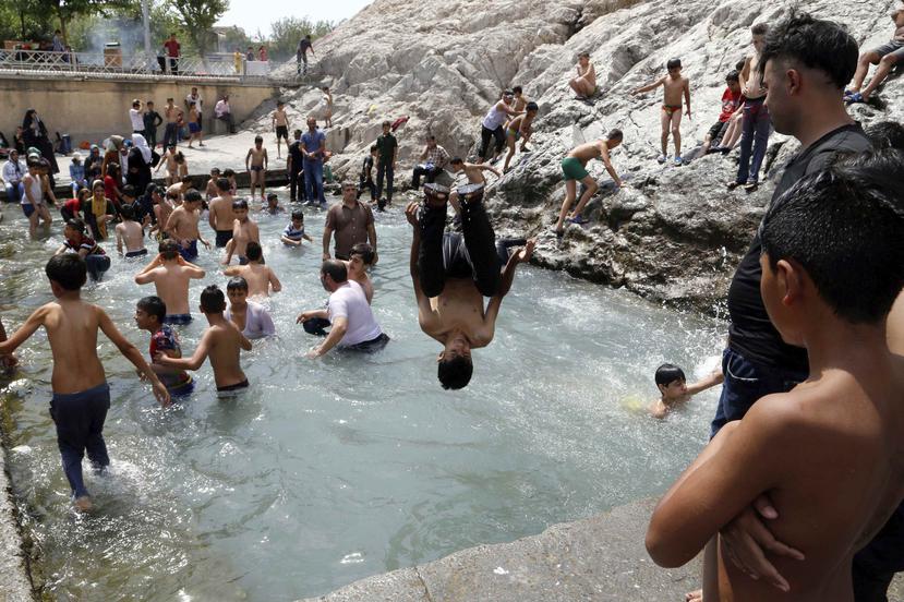 Un grupo de niños se refrescan en la piscina de Cheshme-Ali en la antigua ciudad iraní de Ray, en Irán, que también sufre una ola de calor con temperaturas que rondan los 104 grados. (EFE)